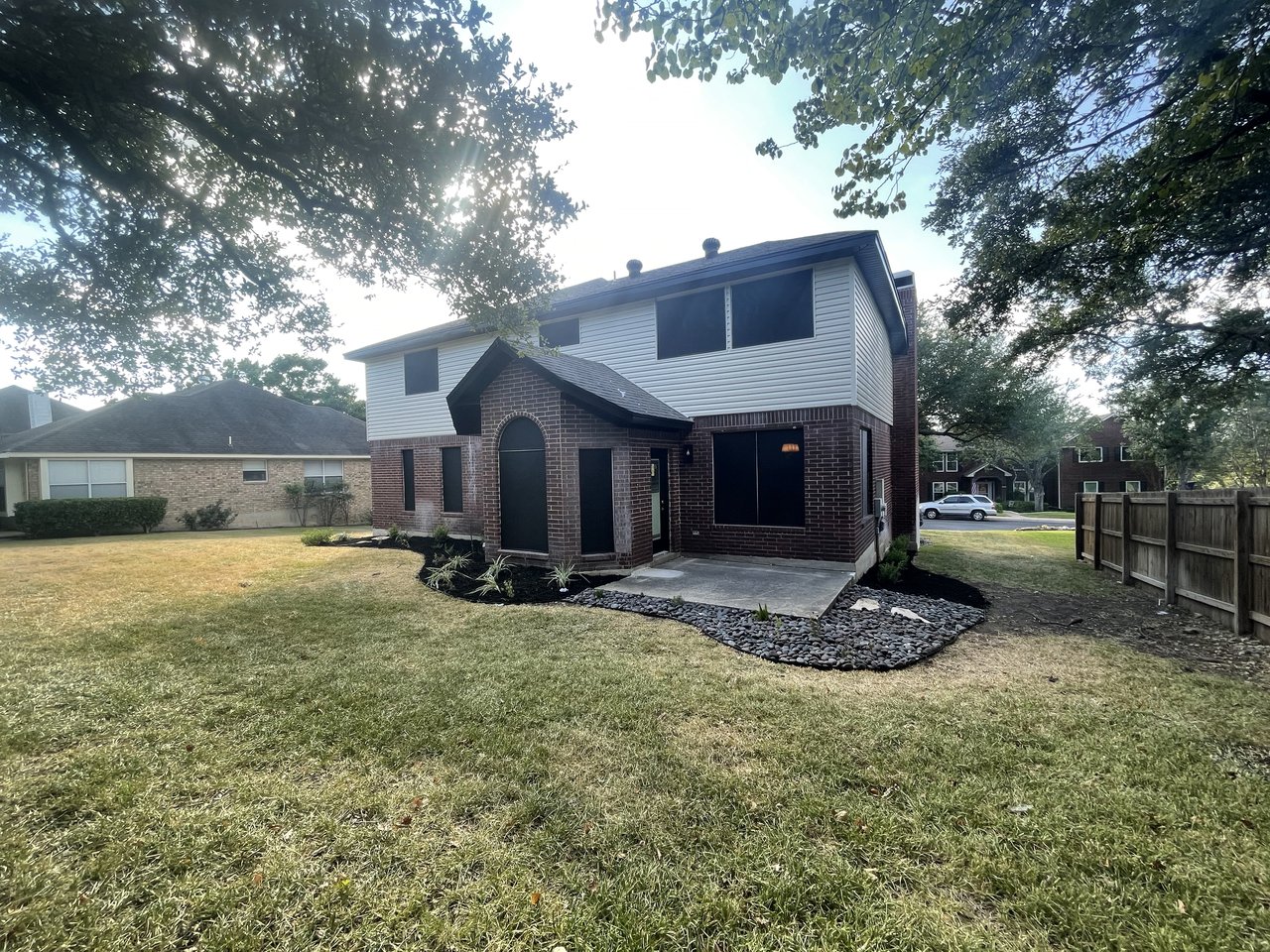 Rear elevation of two-story home with brick and siding, black solar screens on upper windows